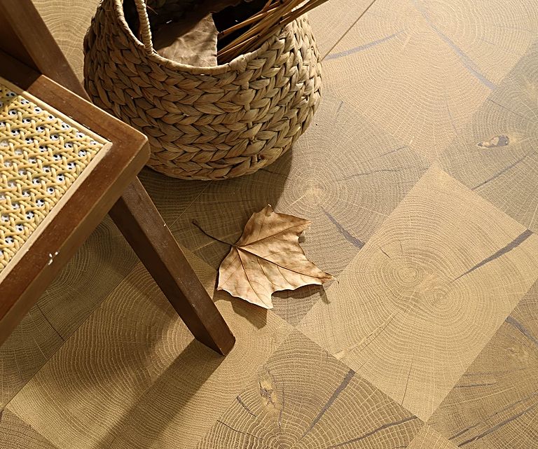 Close view of a parquet-style wood-grain floor beside woven furniture