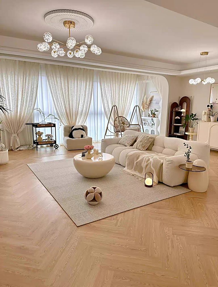 A lounge laid with light oak herringbone flooring, seen beneath a sofa, rug and a glass pendant light.