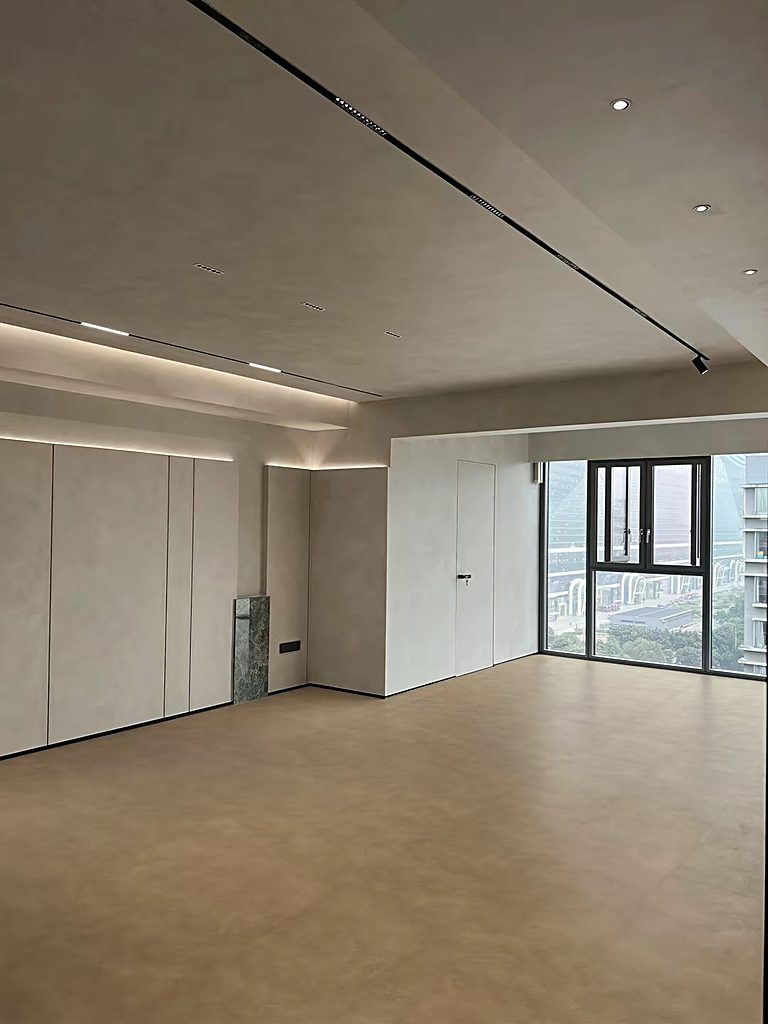 A large open hall finished in large-format stone-look flooring, with full-height glazing at the far end.