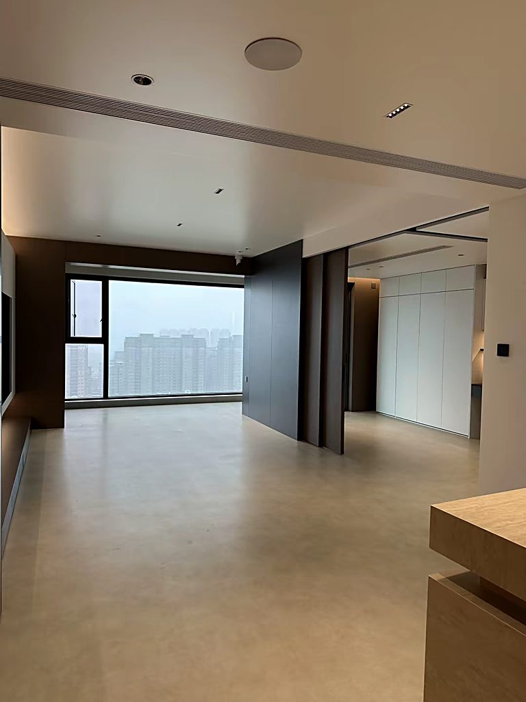Large-format stone-look flooring in a modern interior, leading towards a window with a city view.